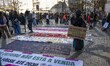 A woman carries a placard with environmental and protest slogans and walks near some banne...