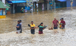 Several residents walk through floodwaters in the Kaduwela town area after heavy rains fro...