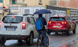 A man rides a bicycle and holds a blue umbrella to shield from heavy rain as he cycles bet...