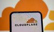 In this photo illustration, the Cloudflare logo appears on a cell phone with another compa...