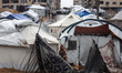 Palestinians walk outside their tent at a makeshift camp sheltering displaced Palestinians...