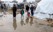 Palestinians walk outside their tent at a makeshift camp sheltering displaced Palestinians...