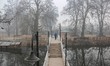 A man walks over a wooden bridge on a cold and foggy winter morning in Srinagar, Jammu and...