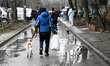 A woman walks a dog on a lead while carrying a bag outside a residential building damaged...
