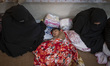Veiled Afghan female refugees sit beside a young Afghan boy sleeping in the Milak refugee...