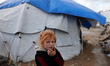 A displaced Palestinian girl plays outside her tent shelters as the eastern Mediterranean...