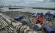 People assemble nets on top of piles of shell waste in Cilincing, Jakarta, Indonesia, on J...