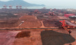 Large machinery stacks and stores iron ore in the cargo yard at the Xinsu Port Terminal in...