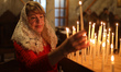 A worshipper lights a candle during the Christmas morning service at the Greek Orthodox Ch...
