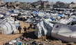 Palestinians walk among tents sheltering displaced Palestinian families in Gaza City, Pale...
