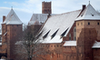 A section of Malbork Castle appears through a train window during a winter rail journey in...