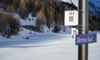 A blue station sign for Bernina Suot is mounted on a metal pole alongside railway technica...