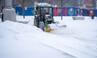 A tractor equipped with a rotating brush clears snow and slush from pedestrian areas at Ce...