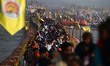 Hindu devotees cross a pontoon bridge as they arrive to take a holy dip on the eve of ''Ma...