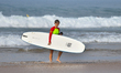 A tourist walks along Narigama Beach carrying a surfboard in Hikkaduwa, Sri Lanka, on Janu...