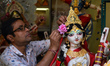 An artisan applies the final touches to a Saraswati idol in a pottery hub in Kolkata, Indi...