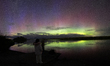 People look at the Aurora Australis, also known as the Southern Lights, as it glows on the...