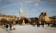 People stroll along the snow-covered Tuileries Gardens with the Louvre Museum in the backg...