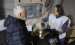 Volunteers serve free hot meals to residents at a mobile heating point operated by the Sta...