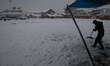 A shopkeeper clears snow near his shop amid heavy snowfall in Sopore, Jammu and Kashmir, I...