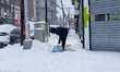A person clears snow from a sidewalk as winter storm conditions continue in New York, New...