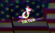 The TikTok logo with a glitch effect is displayed on the screen of a smartphone placed on...