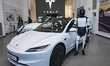 A person dressed in a Tesla Optimus humanoid robot costume poses next to the newly release...