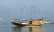 Traditional dhow boats are in the harbor as heavy fog blankets the West Bay skyline in Doh...