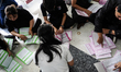 Thai electoral officials check ballot papers and ballot boxes during preparations for voti...