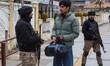 An Indian paramilitary soldier questions a man during a random security check in Srinagar,...