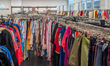 Racks of diverse used apparel and textiles fill the interior of a second-hand retail store...