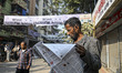 A man reads a newspaper outside of the polling center during Bangladesh's general election...