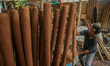 A worker mixes material onto a stick to make incense sticks, commonly referred to by local...