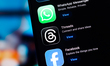 The WhatsApp, Threads, and Facebook logos are displayed on a smartphone screen in the Appl...