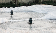 Unusual foam appears at a water refinery plant's discharge outlet, indicating elevated lev...