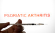 The word PSORIATIC ARTHRITIS appears on a computer screen with a medical syringe in this p...