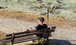A man sits on a wooden bench beside a clear alpine stream in Ramsau, Bavaria, Germany, on...