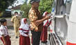 Students, teachers, and residents queue to make deposits at the BTN mobile banking service...