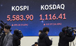 Journalists and television camera crews film the closing market figures displayed on a lar...