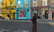 Colorful buildings, shops, and pedestrians line Portobello Road in the Notting Hill distri...