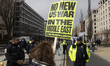 A woman holds signs while protesters gather outside the White House to react to the U.S. a...