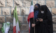A veiled Iranian woman holds a national flag while participating in a protest gathering ag...