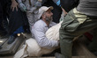 An Iranian worker carries the body of a man killed during the U.S.-Israeli military campai...