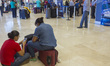 Passengers wait inside the airport terminal after several flights are canceled following a...
