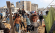 Palestinians inspect the site of an Israeli strike on a tent camp sheltering displaced peo...
