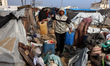 Palestinians inspect the site of an Israeli strike on a tent camp sheltering displaced peo...