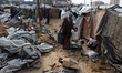 Palestinians inspect the site of an Israeli strike on a tent camp sheltering displaced peo...