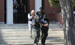 A Greek police officer escorts a Turkish officer who fled to Greece by helicopter after la...