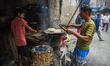 A man cooks using coal-fired ovens amid a shortage of commercial LPG cylinders in Kolkata,...