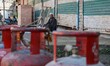 A Kashmiri man sits near the empty liquefied petroleum gas (LPG) cylinders outside a gas a...